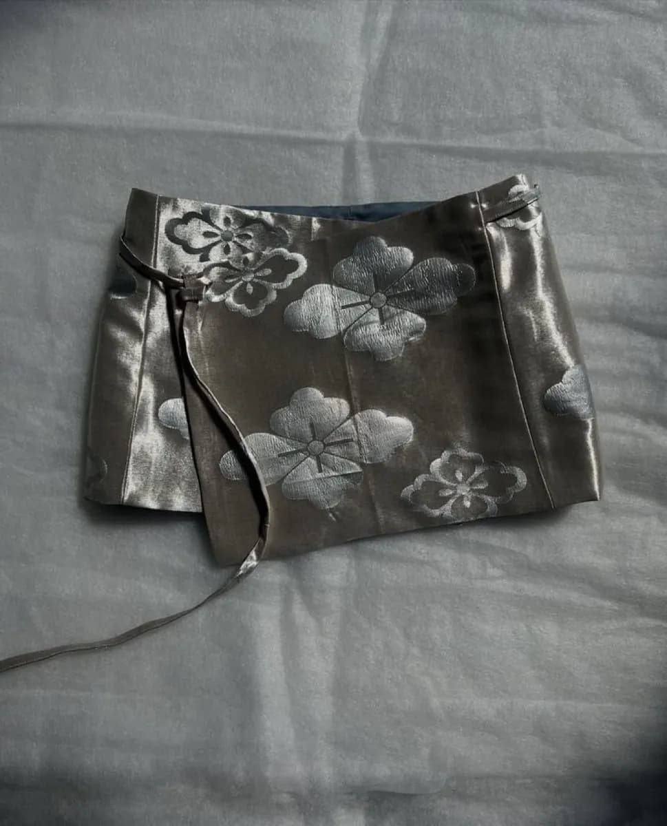 Silver-grey brocade wrap mini skirt with cloud and flower motifs laid on grey fabric
